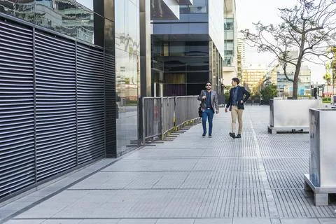 Two colleagues walking on the street while talking about the past meeting Stock Photos