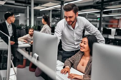 Two colleagues work together. A man shows work on a computer screen. Business Stock Photos