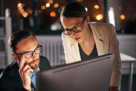 Two colleagues working on computer at night Stock Photos