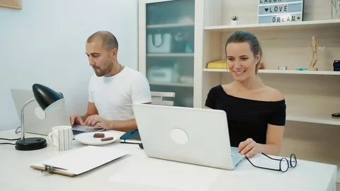 Two colleagues working on laptop and eating together at office Stock Footage 82598736