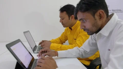 Two colleagues working on their computers share, discuss and talk about work and Stock Footage 100026667