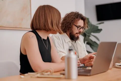 Two colleagues working together on project while sitting on the desk in cozy Stock Photos