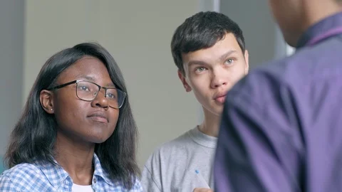 Two college students asking questions to unrecognizable teacher Stock Footage 105193349