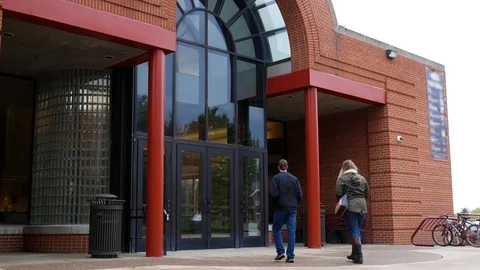 Two College Students walk into generic student union building Stock Footage 81638740