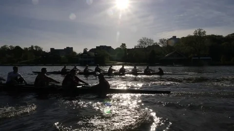 Two collegiate crew boats racing with sun behind them Stock Footage 80650068