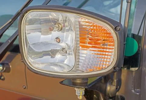Two-color headlight on a side of the tractor cabin Stock Photos