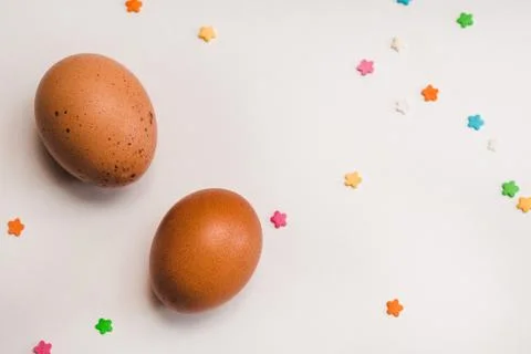 Two colored chicken eggs and pastry decorations on a light background Stock Photos