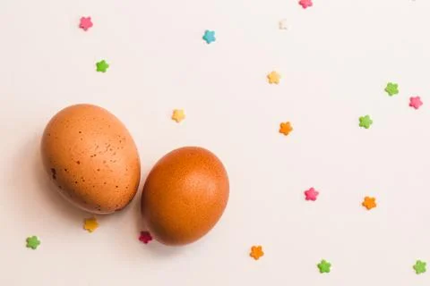 Two colored chicken eggs and pastry decorations on a light background closeup Stock Photos