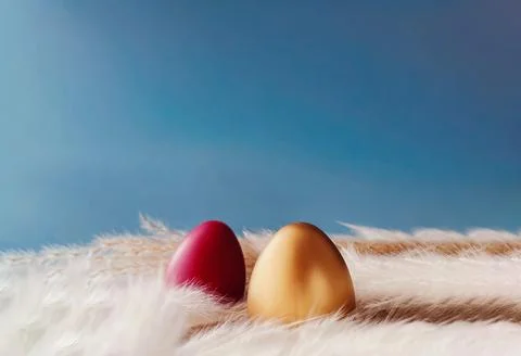 Two colored Easter eggs, gold and red, resting among light pampas plumes ag.. Stock Photos