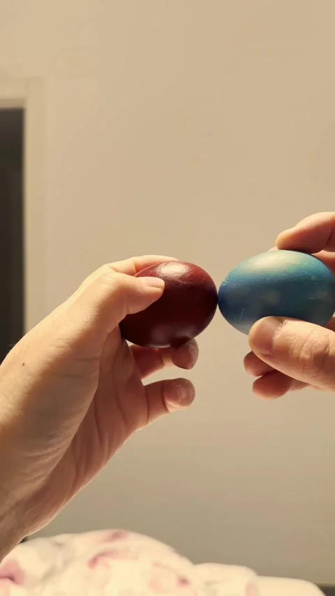 Two colored easter eggs knocking together traditional holiday game closeup Stock Footage 332592172