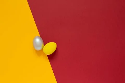 Two colored painted eggs on colored yellow and red background Easter card wit Stock Photos