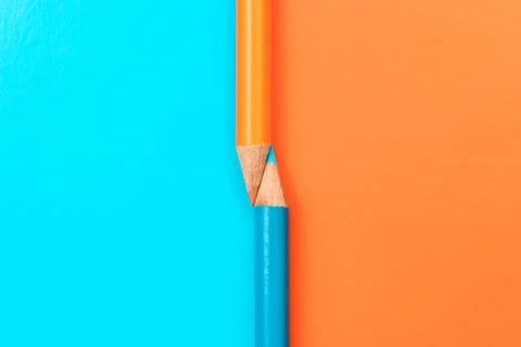 Two colored pencils on the border of different colors. Stock Photos