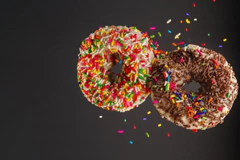 Two colored sweet donuts on a gray background. Levitation. Confectionery, caf Stock Photos