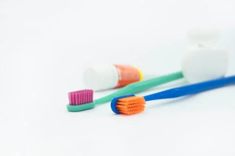 Two colored toothbrushes and small tube of paste and dental floss Stock Photos