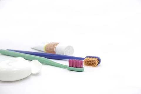 Two colored toothbrushes and small tube of paste and dental floss Stock Photos