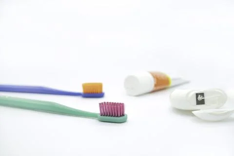 Two colored toothbrushes and small tube of paste and dental floss Stock Photos