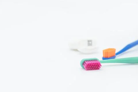 Two colored toothbrushes with bright orange and red bristles and dental floss Stock Photos
