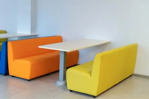 Two colorful armchairs sofas with a table in the room. Yellow and orange benc Fotos Stock