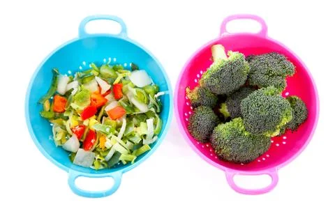 Two colorful colanders with vegetables Stock Photos