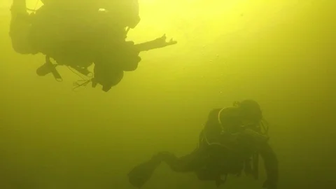 Two combat swimmers diving underwater in green waters with the weapon in hands Stock Footage 121858502