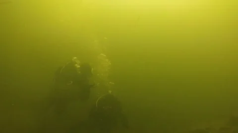 Two combat swimmers moving underwater in green waters with the weapon in hands Stock Footage 121858490