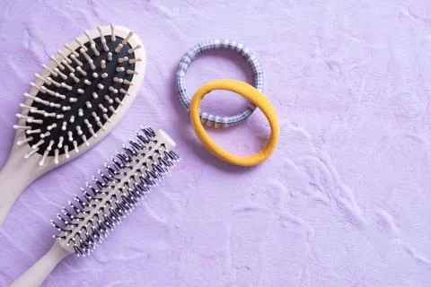 Two combs and elastic bands for hair lie on a textured background Stock Photos