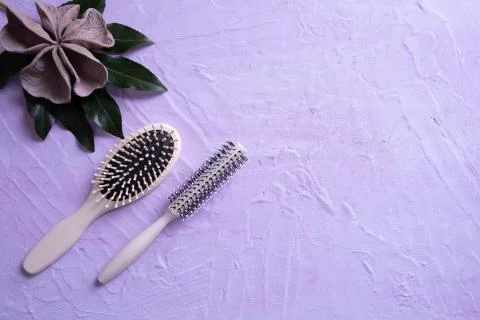 Two combs lie on a textural background, a green leaf and decoration on top Stock Photos