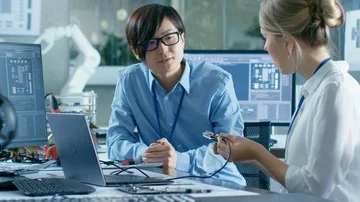 Two Computer Engineers Talking, They Connect Printed Circuit Board to a Laptop Stock Footage 85771556