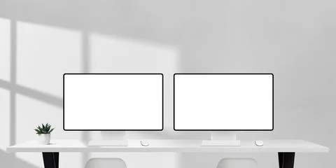 Two computer monitors with blank screens on white office desk, sunlight and.. Stock Photos