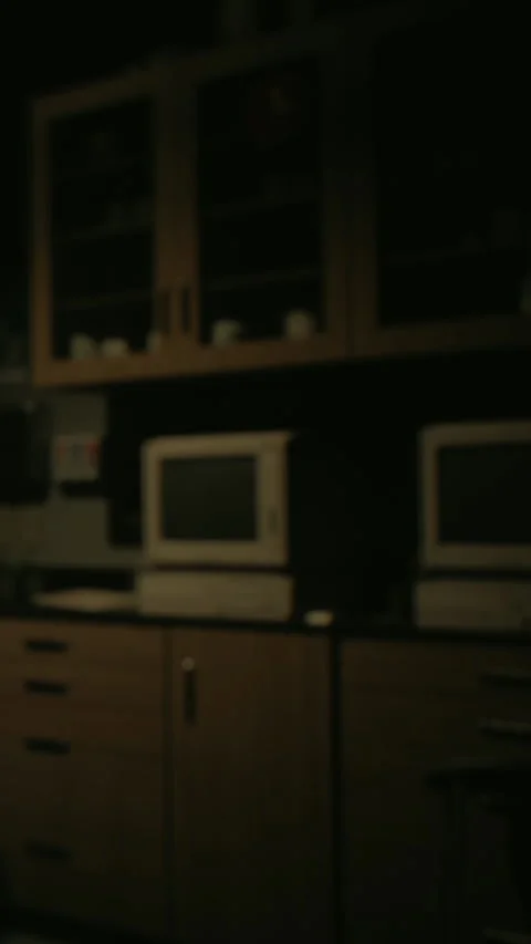 Two computer monitors in a dim kitchen with wooden cabinets and shelves Stock Footage 340259062