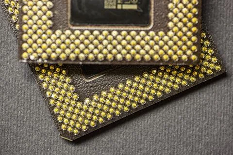 Two computer processors showing golden pins resting on dark background Stock Photos