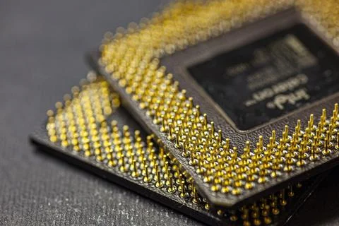 Two computer processors showing golden pins resting on dark surface 写真素材