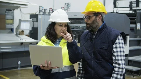 Two concentrated technicians standing at factory with laptop Stock Footage 127340832