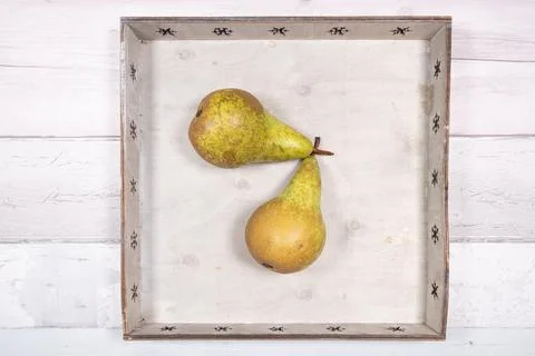 Two conference pears placed in an old wooden tray on an old wooden floor Stock Photos