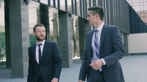 Two confident and smart-looking business men walking along office building Stock-Footage 68971542