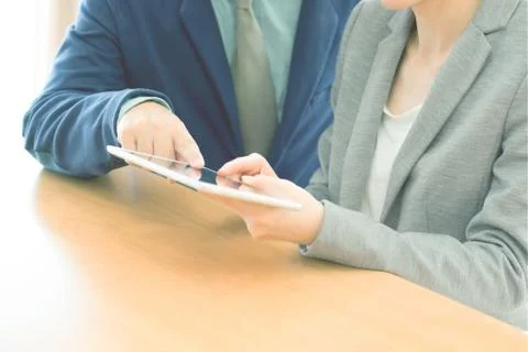 Two confident businesspeople using a digital tablet together while working at Stock Photos