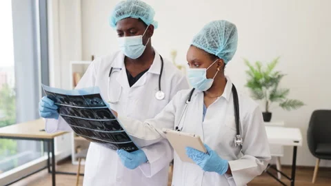 Two confident doctors analyzing patient scan and taking notes in modern hospital Stock Footage 316208758