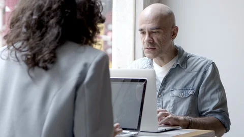 Two confident people sitting at table and using laptops Stock Footage 121001265