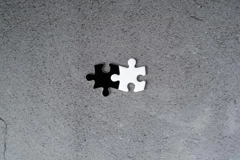 Two connected jigsaw puzzle pieces in black and white on grey background Stock Photos