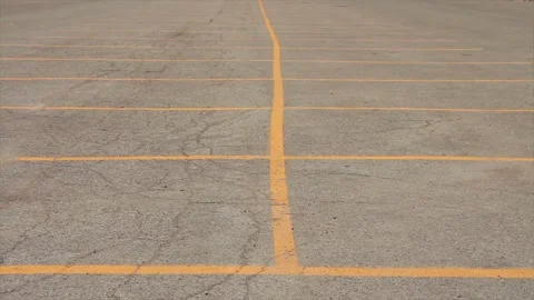 Two connected rows of empty parking spaces in parking lot marked with yellow Stock-Footage 246611671