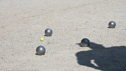 Two consecutive petanque throws on a gravel court, with metal balls landing near Stock Footage 310570913