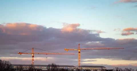 Two construction cranes against the backdrop of a thundercloud at sunset Stock-Fotos