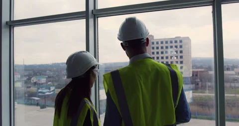 Two construction engineers standing indoors near big window looking at the Stock-Footage 153265063
