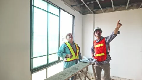 Two construction engineers wearing safety vests and helmets inspect the ceiling. Stock Footage 311374868