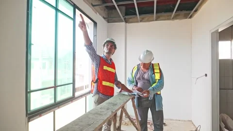 Two construction engineers wearing safety vests and helmets inspect the ceiling 動画素材 321448815