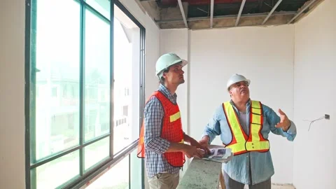 Two construction engineers wearing safety vests and helmets inspect the ceiling Video stock 321448819