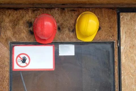 Two construction hard hats on the wall with warning sign 库存照片