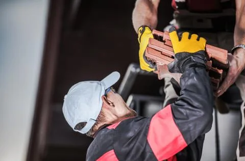 Two Construction Male Workers Unloading Orange Ceramic Roof Tile And Placing  Stock Photos