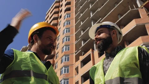Two construction managers in helmets discuss the details of construction Stock Footage 105678270