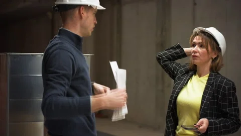 Two construction professionals, man and woman wearing hard hats, have tense.. Stock Footage 329645582